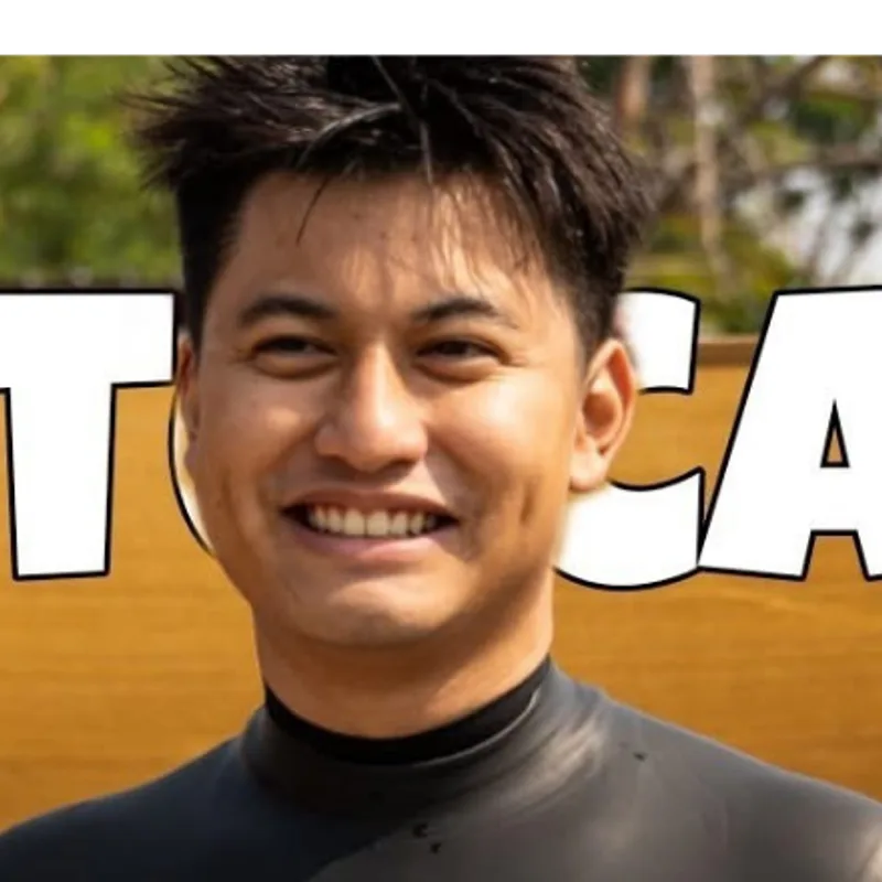 Keng ยืนยิ้มและยกนิ้วโป้งในชุดเว็ตสูทหลังทำผลงานที่ดีที่สุด